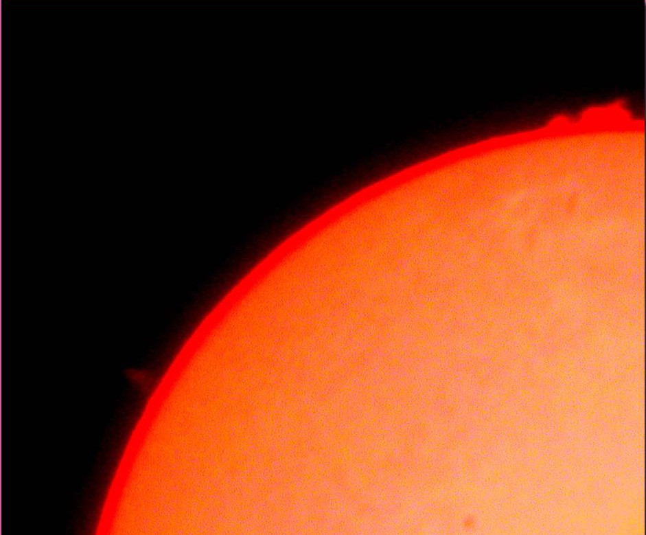 Zugna, 05.07.04. Il Sole di fine luglio è particolarmente attivo: sulla sua superficie sono presenti macchie di notevoli dimensioni (equivalenti a diverse volte il diametro terrestre) ed enormi protuberanze (getti di gas incandescenti). Queste ultime possono essere osservate solo durante le eclissi totali di Sole o con un filtro H-alpha, il quale lascia passare solo un particolare tipo di rosso, quello emesso dalle protuberanze. All'osservatorio del monte Zugna, sul telescopio rifrattore, è montato il filtro H-alpha col quale è stata ottenuta la foto. (foto e testo Ochner)
